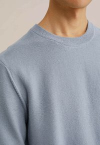 Light blue knit sweater with a round neck, ribbed collar, and subtle texture. Focus on the upper part, showing shoulder and neckline details.