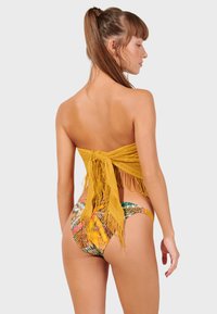 Bikini s bandeau vrchom s žltými fricami a spodkami s viacfarebným vzorom s detailom bočného krúžku. Hladký povrch a priedušná látka.