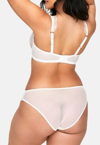 Biały koronkowy stanik i dopasowane przezroczyste majtki. Stanik ma regulowane ramionka i delikatne wykończenie. Miękki, lekki materiał, dopasowany krój.
