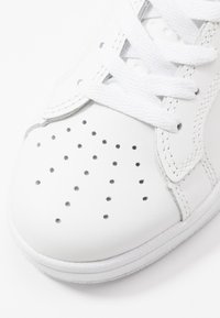 Sneaker in pelle bianca caratterizzato da una finitura liscia, design con punta perforata, lacci bianchi e suola in gomma bianca testurizzata.