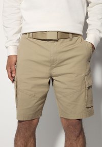 Khaki cargo shorts with a textured design, featuring side pockets and a flat waistband with a matching belt.