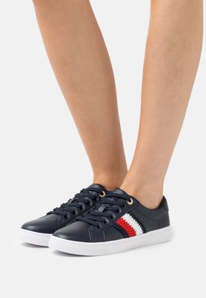 Sneakers in pelle navy con suola bianca, caratterizzati da una striscia testurizzata in rosso e bianco. Design con lacci e occhielli in tono oro, dalla texture morbida.