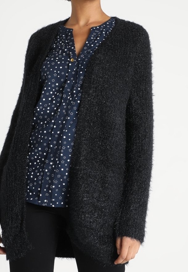 Czarny, miękki kardigan z długimi rękawami i otwartym przodem, noszony na ciemnoniebieskiej koszuli zapinanej na guziki, zdobionej białym wzorem gwiazdek.