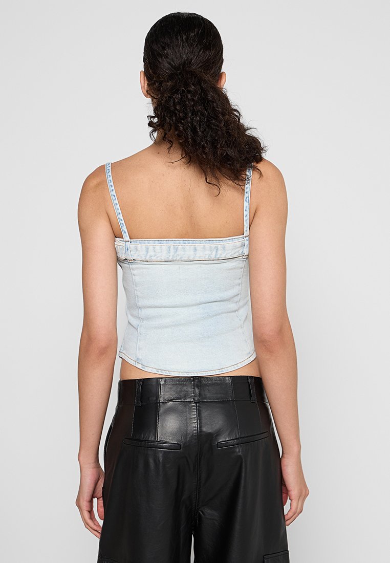 Hellblaues Denim-Crop-Top mit dünnen Trägern, figurbetontem Design und cropped Saum. Die Rückseite hat eine saubere Verarbeitung ohne Verzierungen.