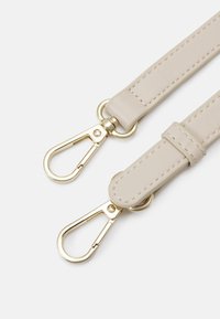 Beige läderrem med guldfärgade detaljer, utrustad med två svängklipp och sömda detaljer. Slät yta och ren design.