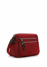 Sarkans auduma soma ar divām priekšējām rāvējslēdzēju kabatām, brūniem akcentiem, regulējamu siksnu un taisnstūra formu. Gluda tekstūra un izturīgs dizains.