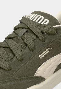 Olive green suede sneaker with textured laces, a white Puma logo, and a contrasting light beige side stripe. Features a soft lining.