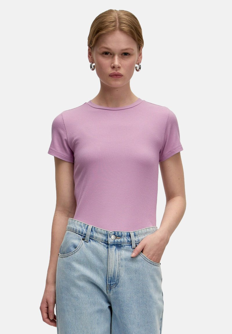 Lichtpaarse geribde T-shirt met korte mouwen en een ronde halslijn, gecombineerd met lichtblauwe spijkerbroek met hoge taille.