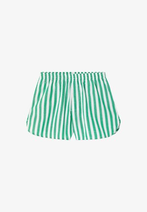Enfant aux longs cheveux blonds portant une chemise oversize rayée verticale verte et blanche ainsi que des shorts assortis avec des tongs marron.