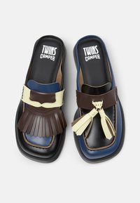 Due sandali slide caratterizzati da una combinazione di pelle marrone, blu e crema, con dettagli arricciati e nappine sulla parte superiore. Plantari neri testurizzati.