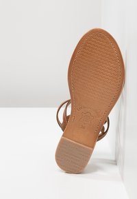 Bruine leren sandalen zool met textuurpatroon en merkdetails. Contouren zijn gebogen; heeft een plat ontwerp. Maat aangegeven als 36.