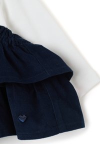 Top bianco con una gonna di velluto a coste blu navy arricciata. La gonna presenta un accento a forma di cuore blu navy con la parola "amore" stampata sopra.