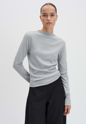 Chemise grise à manches longues en texture côtelée avec un col bateau, associée à un pantalon noir taille haute. Design simple et ajusté.
