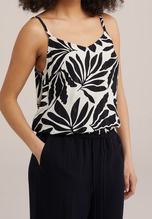 Czarna i biała koszulka na ramiączkach z wzorem liści, wykonana z lekkiego materiału o luźnym kroju, zestawiona z ciemnymi, teksturowanymi spodniami.