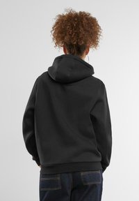 Juodas džemperis su reguliuojama gobtuvu, minkšta tekstūra ir raukšlėtomis rankogaliais. Atsarginė pusė parodo laisvą siluetą ir elegantišką dizainą.