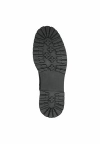 Semelle de chaussure en caoutchouc noir présentant des rainures profondes et un motif texturé pour une meilleure adhérence, avec un bout arrondi et une zone de talon renforcée.