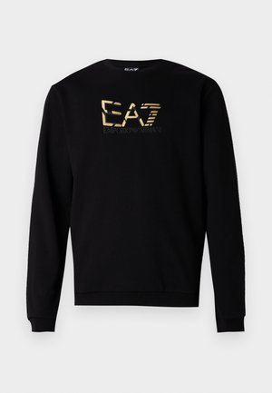 Juodas džemperis iš minkštos medžiagos, pasižymintis apvalia iškirpte ir ilgomis rankovėmis, puoštas auksiniu logotipo dizainu ant krūtinės.