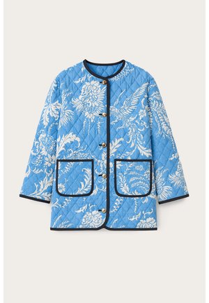 Pikowana kurtka w jasnoniebieskim kolorze z białym wzorem kwiatów i ptaków. Posiada okrągły dekolt, złote guziki oraz granatowe wykończenia z dwoma przednimi kieszeniami.