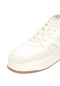 Weißer Sneaker mit einem Obermaterial aus glattem Leder und Wildlederakzenten, perforierter Zehenpartie, weißen Schnürsenkeln und einer strukturierten Gummisohle.