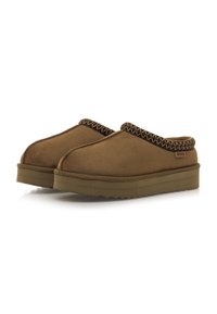 Zapatos marrones de tipo slip-on hechos de ante, con un ribete texturizado y estampado a lo largo del collar y una suela gruesa de goma con un borde serrado.