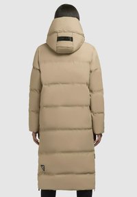 Lungo piumino beige con un esterno testurizzato, cappuccio e accento logo nero. Presenta una trapuntatura orizzontale e tasche laterali con zip.