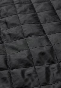 Zwart gewatteerde stof met een gladde textuur, voorzien van een ruitpatroon en contrasterende stiksels, voornamelijk in een matte afwerking.