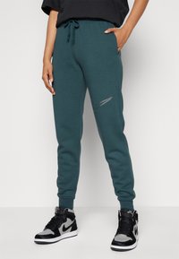Nike Sportswear CLUB SHINE PANTS - Teplákové kalhoty - deep jungle