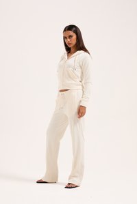 Tuta color crema con felpa con zip e pantaloni con pantaloni elasticizzati, entrambi in un tessuto morbido e liscio con dettagli sottili.