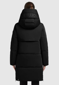 Black insulated puffer coat with a large hood, featuring a Khujo logo at the back, quilted sections, and side zippers at the hem.