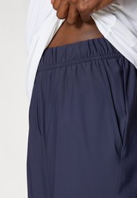 Ναυτικές αθλητικές βερμούδες με ελαστική ζώνη, πλαϊνές τσέπες και λεπτομέρειες από δίχτυ. Συνδυασμένες με λευκό μπλουζάκι, που δείχνει απαλή υφή υφάσματος.