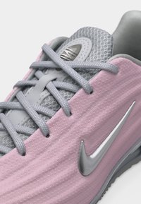 Κοντινό πλάνο ροζ και γκρι αθλητικού παπουτσιού Nike που δείχνει τα κορδόνια, τη διχτυωτή γλώσσα και το ασημένιο λογότυπο Nike Swoosh στην υφασμάτινη πλευρά.