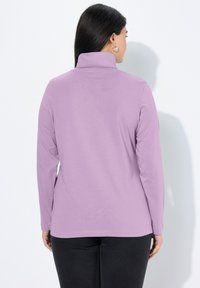 Světle fialové tričko s dlouhým rukávem a rolákem, s hladkou texturou, polopřiléhavým střihem a složeným límcem, kombinované s černými kalhotami.