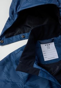 Blå mønstret børnejakke med aftagelig hætte, fleecekrave og indre label, der angiver størrelse 92 til børn i alderen 1,5-2 år.