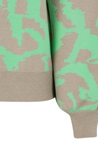 Manche et ourlet de pull en maille beige et vert menthe avec un motif abstrait de feuilles pixellisées et des bords côtelés.