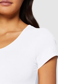T-shirt blanc à manches courtes avec un col rond et une texture lisse et côtelée. Présente des coutures nettes le long des manches et de l'ourlet.