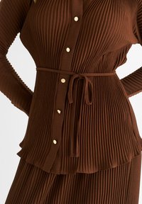 Brown ribbed dress featuring long sleeves, button-front closure with metallic buttons, and a matching tied belt at the waist.