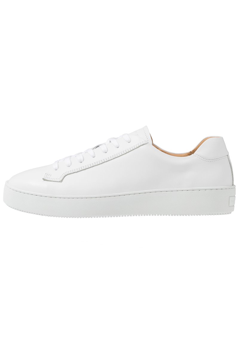 White leather sneaker with a smooth finish, rounded toe, flat lace-up design, and a thick rubber sole featuring a textured grip pattern.
