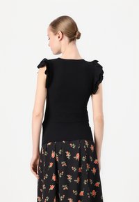 Top nero aderente con maniche a sbuffo, realizzato in tessuto a coste. Presenta un collo rotondo, una superficie liscia e una silhouette snella.