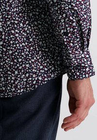 Hemd mit navyblauen und weißen Blumenmuster sowie einem geknöpften Bund. Das Hemd besteht aus weichem Stoff, hat eine schmale Passform und einen abgerundeten Saum.