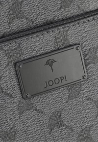 Tessuto grigio testurizzato con una placca a rilievo del marchio Joop! nera, che presenta un logo a ventaglio stilizzato e un dettaglio di bordatura cucita.