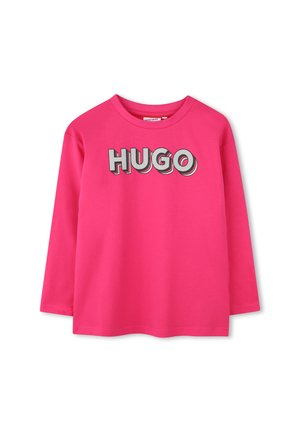 T-shirt à manches longues en coton rose vif, arborant le mot "HUGO" en lettres grises en gras sur la poitrine. Encolure ronde.