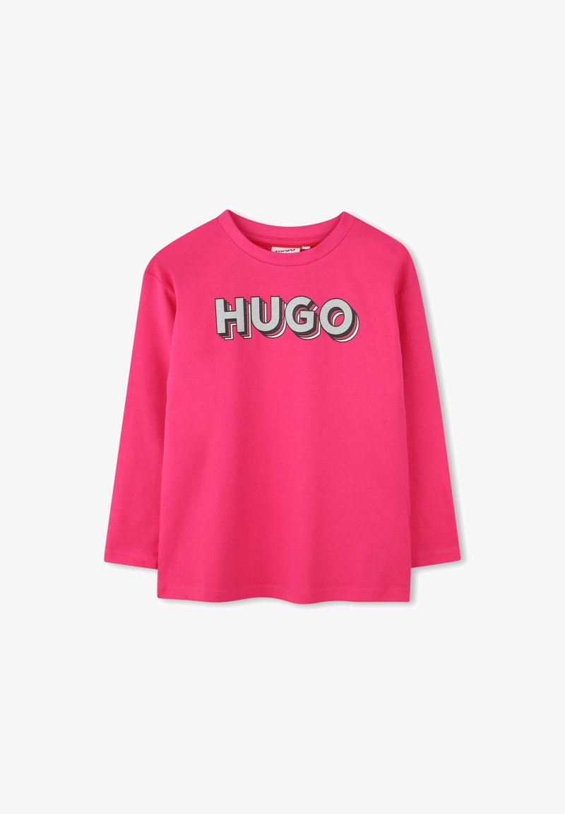 Langemouwen T-shirt van helder roze katoen, met het woord "HUGO" in vet, grijs omlijnd lettertype over de borst. Ronde hals.