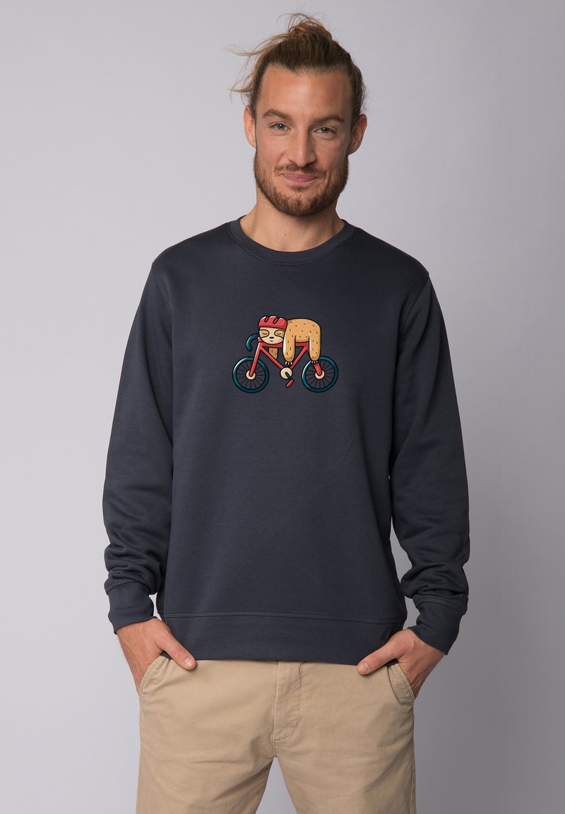 Sweatshirt gris foncé avec un graphique coloré d'un personnage faisant du vélo. Le matériau semble doux, avec une coupe décontractée et un col rond.