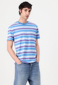 Camiseta de rayas en azul claro, con rayas horizontales en rojo, blanco y azul marino. Cuello redondo, mangas cortas, material de algodón.