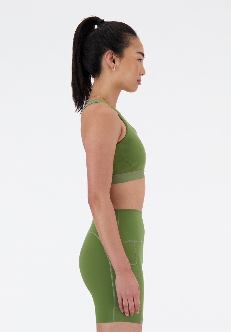 Grüner Sport-BH und hochtaillierte Shorts aus einem glatten, dehnbaren Material. Merkmale sind minimalistische Nähte und ein enganliegendes Design.