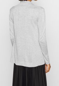 Szary kardigan z długim rękawem o miękkiej fakturze, z kołnierzem i lekko rozkloszowanym dołem. Tył ma prosty krój bez ozdobników.