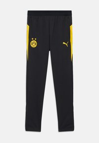 Schwarze Sporthosen mit gelben Akzenten, die ein Logo an der Vorderseite und seitliche Streifen haben. Hergestellt aus einem leichten, atmungsaktiven Stoff.