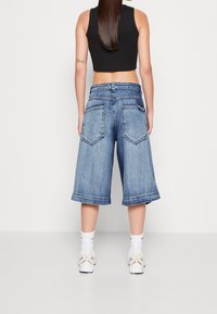 Denim culotter med lös passform och medelhög midja i ljusblått. Med två bakfickor och en upprullad fåll, tillsammans med vita sneakers.