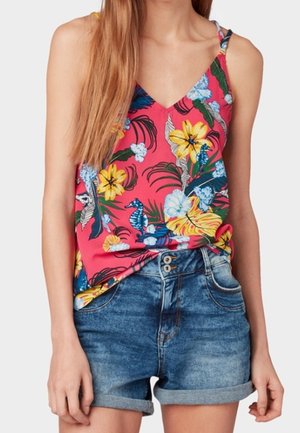 Camiseta sin mangas floral en tela rosa con flores azules y amarillas, combinada con shorts de mezclilla de lavado claro y dos botones, con los dobladillos enrollados.