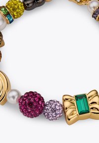 Bracelet coloré à perles avec des accents dorés, une grande pierre précieuse verte et diverses perles texturées aux teintes violettes, roses et noires.